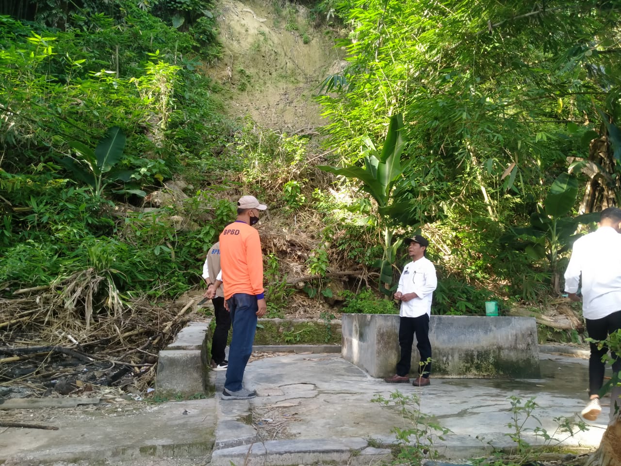 Lurah Kolese, Muhulisi menerangkan lokasi tebing rawan longsor ke personel BPBD Baubau, Jum'at (9/9). Lokasi itu menjadi tempat lalu-lalang nelayan setempat. (Foto Texandi)