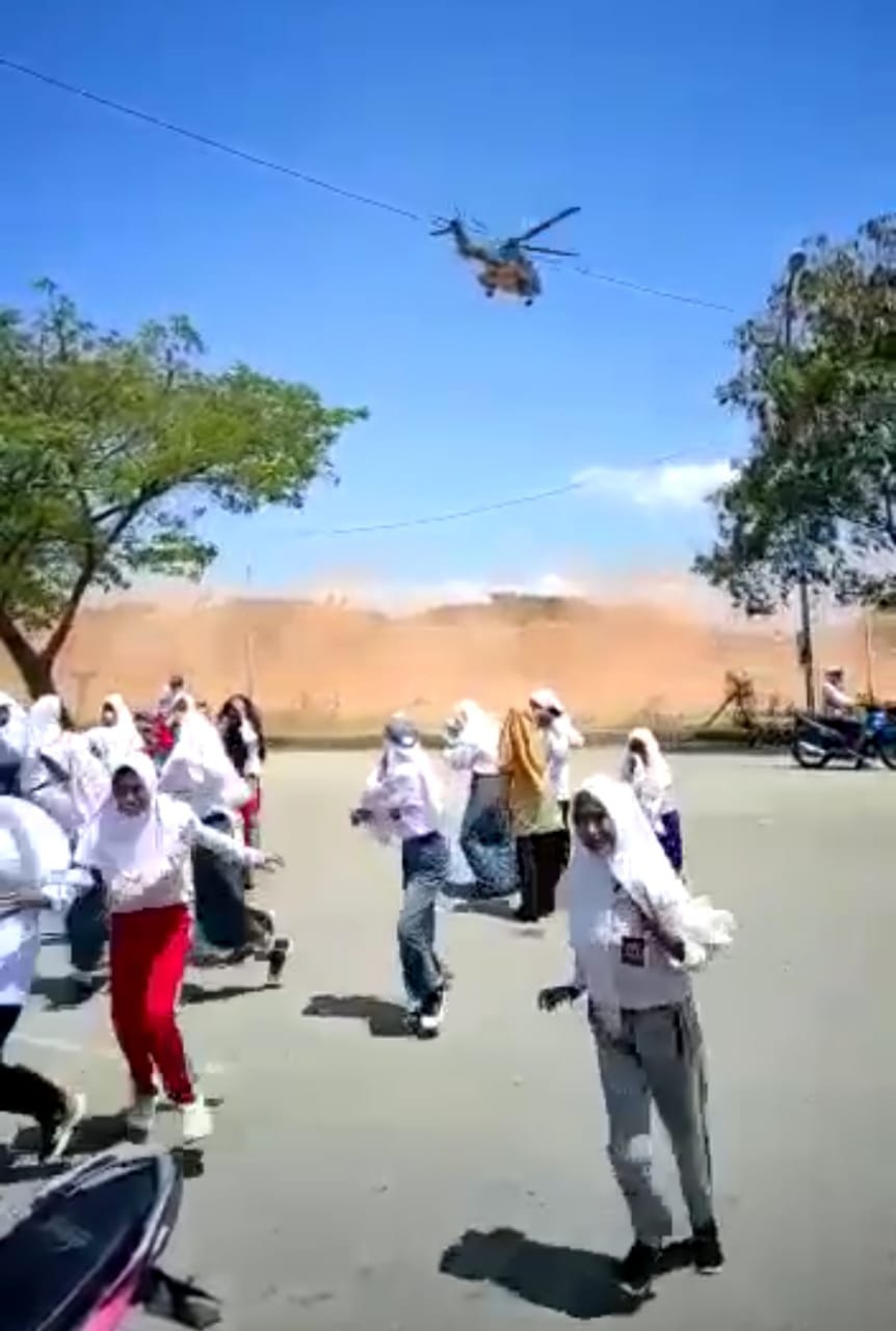 Sejumlah pelajar berhamburan menghindari debu saat helikopter berada di atas lapangan Stadion Betoambari. (Foto Istimewa)